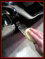 Applying U.V. protectant to foot peg on a motorcycle by Fifty Dollar Detail.